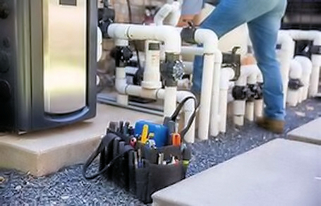 View of a man working on pool plumbing.